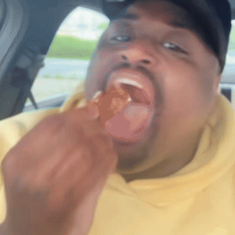 Man in Yellow Hoodie Eating Chicken Wing