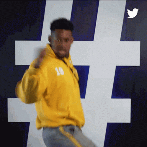 Man In Yellow Jacket Number 18 Dancing In Front Of Twitter Logo GIF