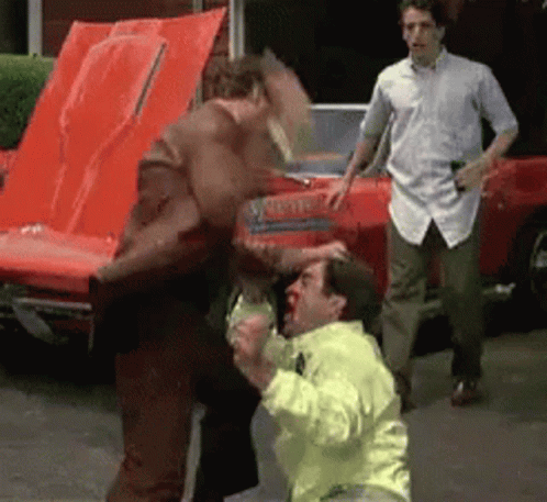 Man In Yellow Jacket Punched By Man In Brown Jacket GIF