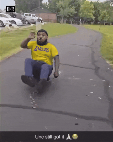 Man In Yellow Lakers Shirt Sliding Down Road GIF