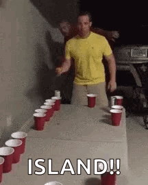 Man in Yellow Shirt at Table With Red Cups and Beer
