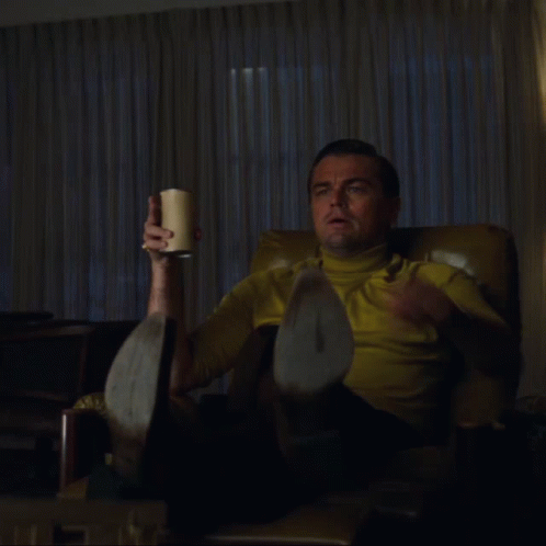 Man in Yellow Shirt Holding Cup and Pointing