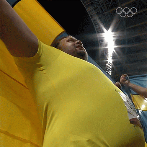Man in Yellow Shirt Holding Olympics Flag