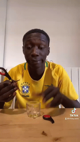 Man in Yellow Shirt Holding Scissors Over Glass
