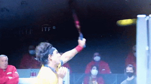 Man in Yellow Shirt Holding Tennis Racket at ITF Sign