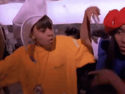 Man In Yellow Shirt Next To Man In Red Hat And Woman In Blue Shirt GIF