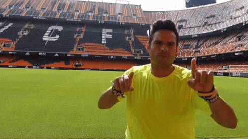 Man in Yellow Shirt Pointing at Stadium