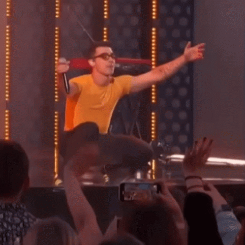 Man In Yellow Shirt Singing Into Microphone GIF