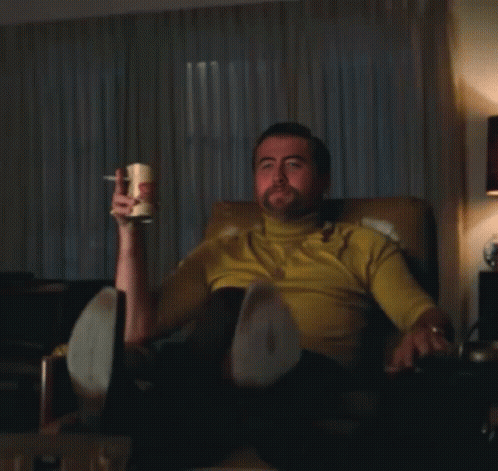 Man in Yellow Shirt Sitting Holding Mug Pointing