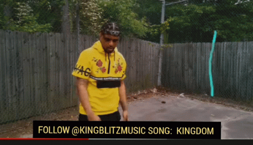 Man in Yellow Shirt Standing in Front of Fence