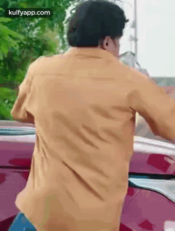 Man in Yellow Shirt Standing in Front of Red Car