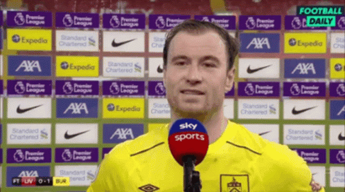 Man in Yellow Shirt Talking Into Microphone