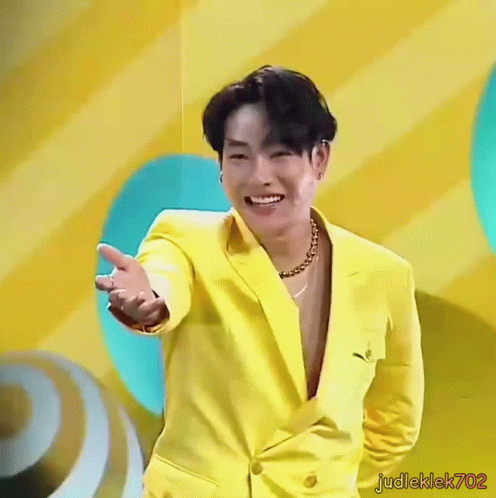Man In Yellow Suit Smiling And Holding Out Hand GIF