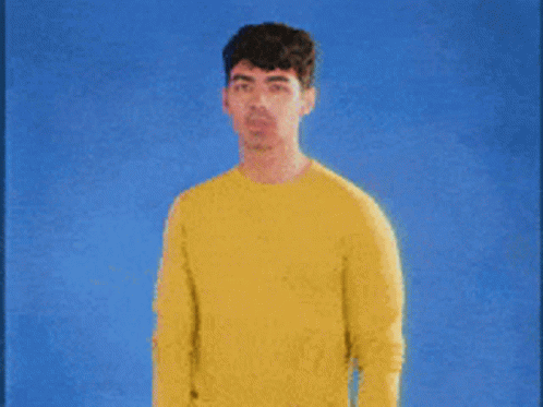 Man In Yellow Sweater Against Blue Background GIF