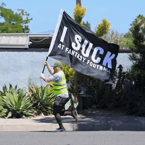 Man in Yellow Vest Running with Flag Saying I Suck at Fantasy Football