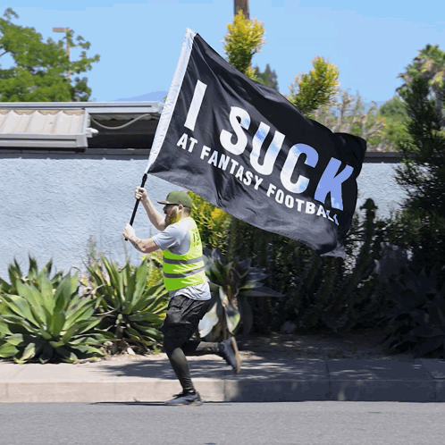 Man in Yellow Vest Running With I Suck at Fantasy Football Flag