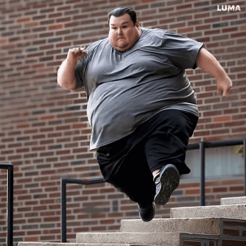 Man Jumping Up Stairs in Front of Brick Building