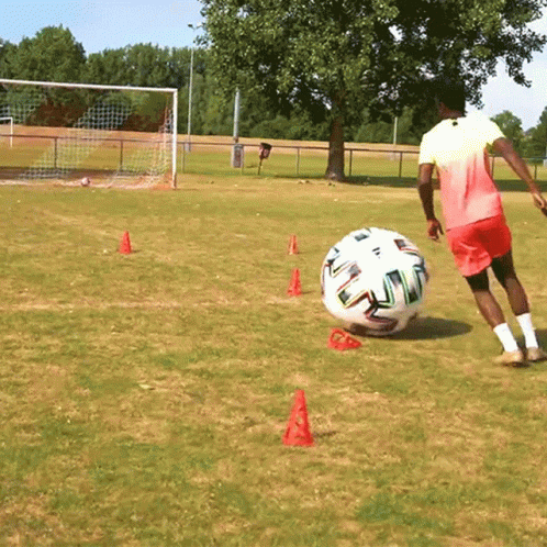 Man Kicking Soccer Ball With Red Cones
