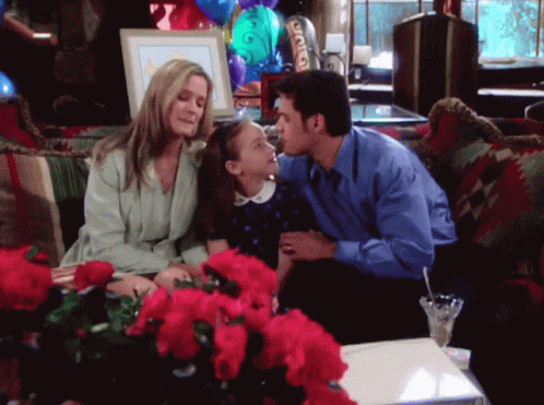 Man Kisses Little Girl On Cheek On Couch With Flowers GIF