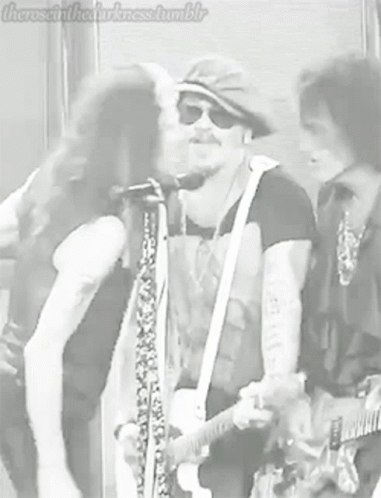 Man Kissing Another Man on Cheek Playing Guitar