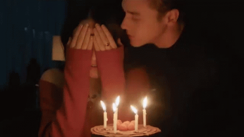 Man Kissing Woman's Cheek Lit Birthday Cake Candles