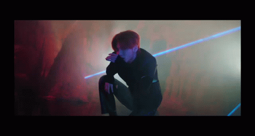 Man Kneeling in Dark Room with Laser