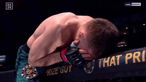 Man Kneeling in Front of Prize Guy Sign