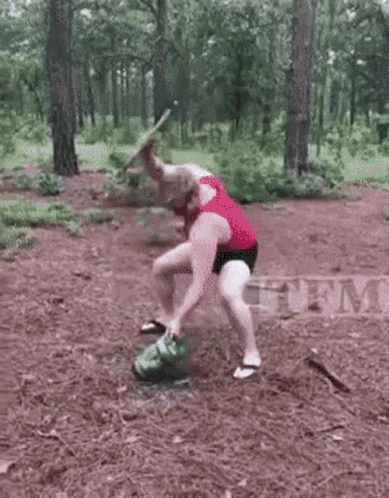Man Kneeling Next To Smoking Watermelon In Woods GIF
