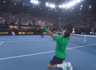 Man Kneeling on Tennis Court Arms in Air