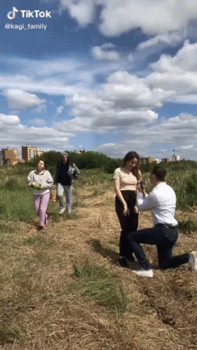 Man Kneeling to Propose to Woman in Field
