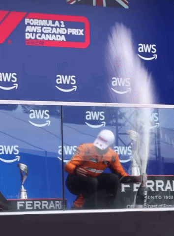 Man Kneeling With Trophy In Front Of AWS Banner GIF