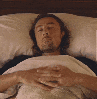 Man Laying In Bed With Eyes Closed And Hands On Chest GIF