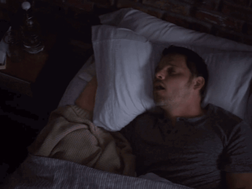 Man Laying in Bed With Pillow on Head