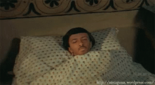 Man Laying in Bed With Polka Dot Blanket