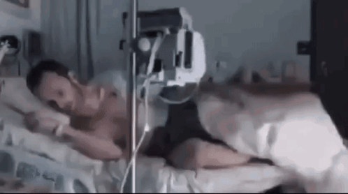 Man Laying in Hospital Bed With IV in Mouth