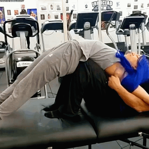 Man Laying on Another Man's Back at Iron Clad Gym