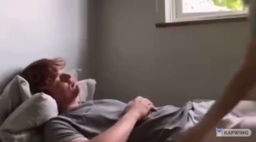 Man Laying On Bed Arms Outstretched By Window GIF