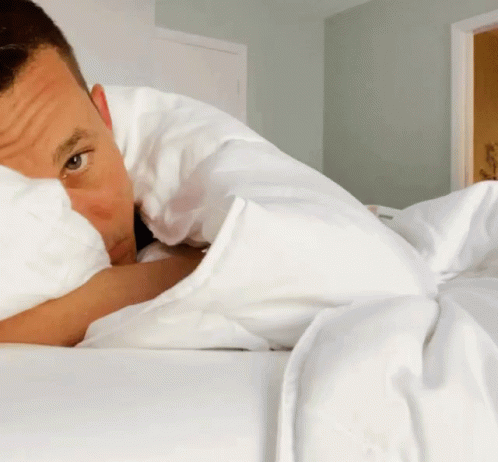 Man Laying on Bed With White Blanket