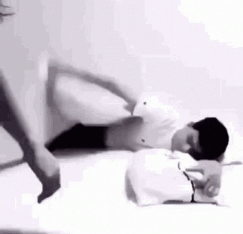 Man Laying on Bed With Woman Standing Next to Him