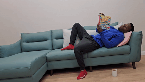 Man Laying on Blue Couch Reading Bobs