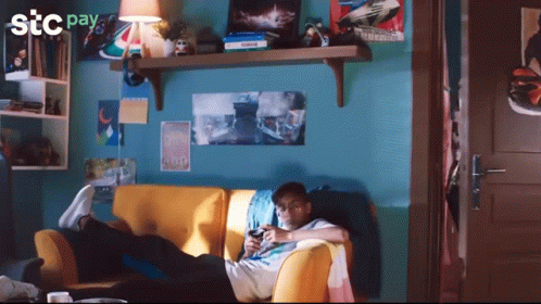 Man Laying on Couch Playing Video Game With STC Pay Logo