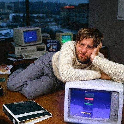 Man Laying on Desk With Microsoft Binder