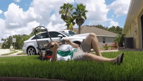 Man Laying On Grass With Lawn Mower GIF