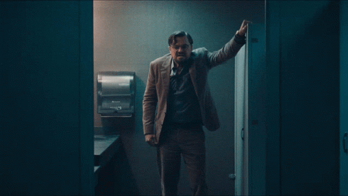 Man Leaning Against Bathroom Wall With Paper Towel Dispenser GIF