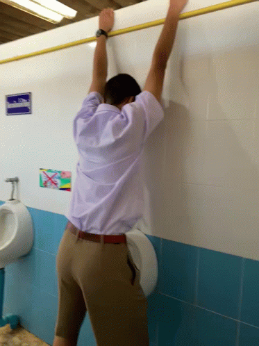 Man Leaning Against Urinal in Bathroom