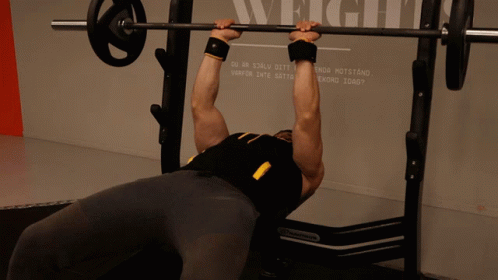Man Lifting Barbell in Front of Wall Saying Weight