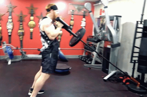 Man Lifting Barbell in Red Wall Gym