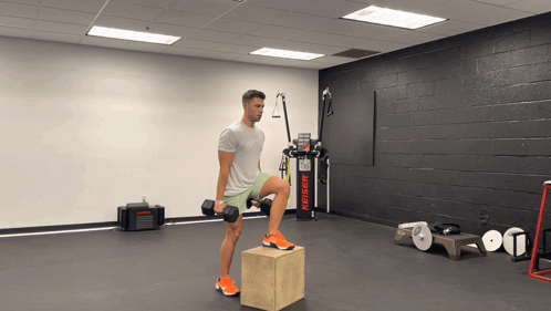 Man Lifting Dumbbell on Box in Gym