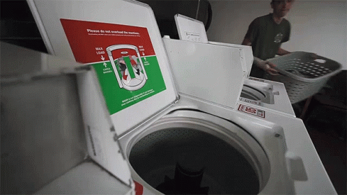 Man Loading Clothes Into Washing Machine Saying Please Do Not Overfill The Machine GIF
