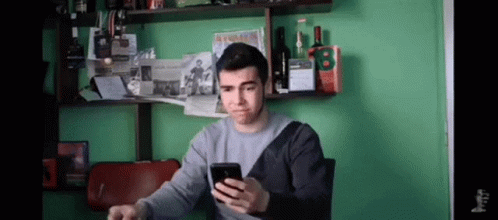 Man Looking at Phone by Green Wall